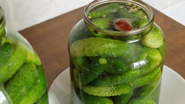 Naturally fermented pickled cucumbers in two jars on kitchen table