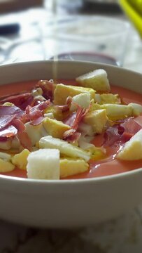 spreading olive oil on salmorejo cordobes, a typical spanish tomato soup