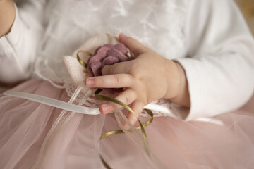 Obraz na płótnie Canvas The hand of a one-year-old girl pulls a flower on a festive dress