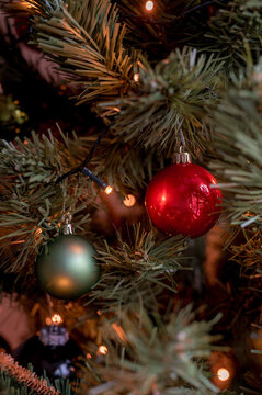 Red and green baubles on Christmas tree with lights.