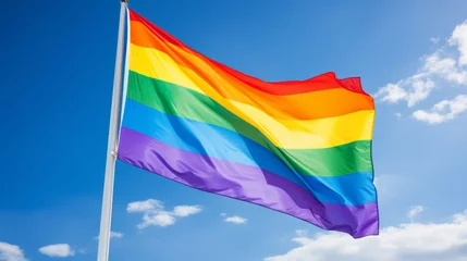 Fotobehang A rainbow flag, LGBTQ+ waving proudly, blue sky © Florian