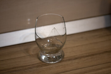 Broken transparent drinking glass in the kitchen. Sharp dangerous pieces.