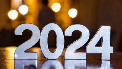 The number 2024 made of silver metal, blurred background of a New Year's Eve party at night