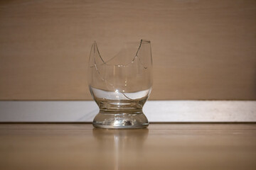 Broken transparent drinking glass in the kitchen. Sharp dangerous pieces.