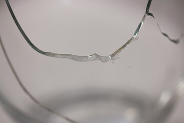Closeup of broken transparent drinking glass in the kitchen. Sharp dangerous pieces.