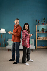 Infidelity, suspicion concept. Young couple standing back to back and using mobile phone, spying to...