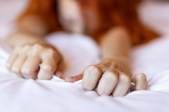 kobieta podczas orgazmu zaciska dłonie w pościeli