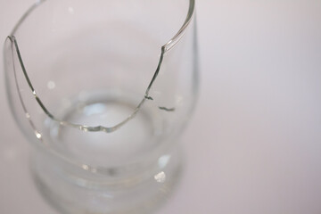 Closeup of broken transparent drinking glass in the kitchen. Sharp dangerous pieces.