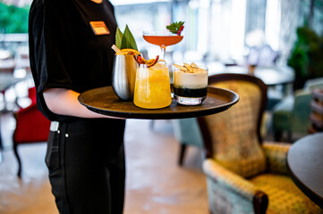 glasses alcohol cocktail set on a waiter tray in bar
