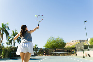 Rear view of a teen girl practicing playing tennis