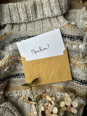 Craft envelope and card with the inscription Hello, warm sweater and flowers