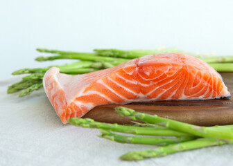 raw salmon and asparagus on a cutting board
