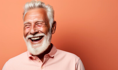 Obraz premium Joyful elderly gentleman with a radiant smile, white beard, and stylish haircut wearing a casual pink polo shirt on a matching peach background
