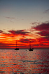 Spectacular sunset observed in the south of Tenerife in December 2023. The figure of several boats is seen in backlight against the red that the clouds take