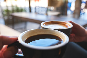 Closeup image of a man and a woman clinking white coffee mugs in cafe