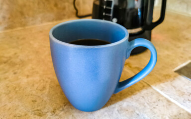 Blue coffee cup and black coffee maker from Mexico.