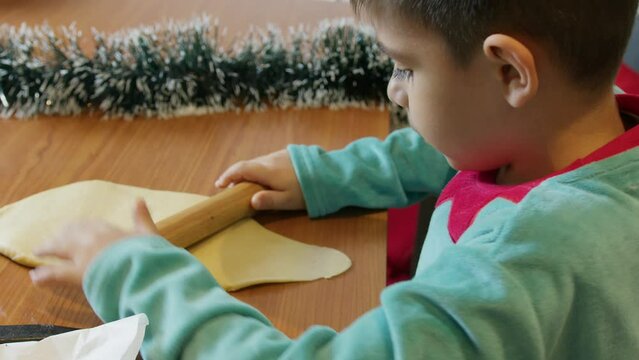 Adorable preschool boy in elf costume using rolling pin to make cookies. Christmas holidays. High quality 4k footage