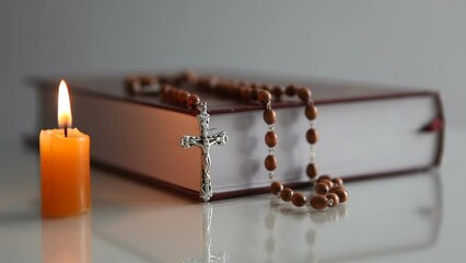 Bible, rosary and burning candle on a light background. Place of prayer for an Orthodox person.