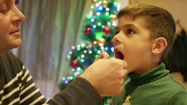 Father putting thread around son's milk tooth. Extraction. Dental care. Christmas. High quality 4k footage