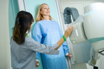 Experienced radiologic technologist preparing female patient for radiography
