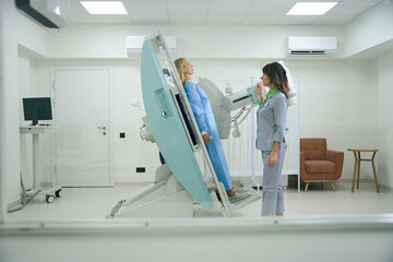 Experienced radiologic technologist preparing adult female for radiography