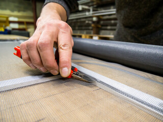 Cutting mosquito net fabric with a knife during the manufacturing process.