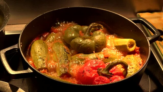 Whole mini courgettes and stuffed peppers cooking in a boiling dish. High quality 4k footage