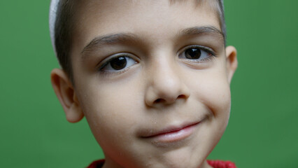 Cute preschool boy winking in slow motion. Close up isolated on green. High quality photo