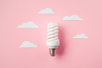 Light bulb with white cut out clouds on pink background. Idea concept. Energy and electricity....
