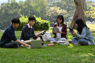 Group of Asian university students reviewing lessons or doing homework together with friends at an...