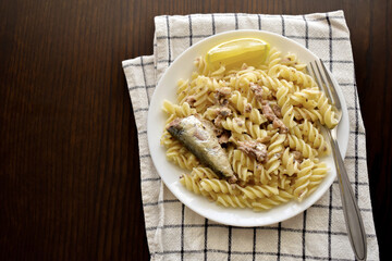 Pasta with sardines with a fork on a white plate. Fusilli with sardines.