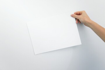 Woman hand holding the paper on white background. place for text. blank piece of inscription paper