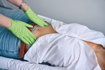 Experienced physician performing abdominal exam of adult person