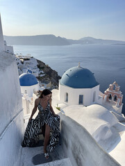 beautiful woman with dark hair in elegant clothes with accessory traveling around Santorini