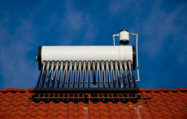 Solar water heater boiler on the rooftop, broken glass tube , blue sky with white clouds.