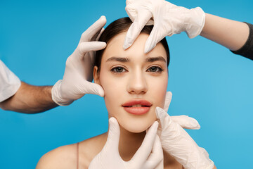 Smiling young woman receiving botox beauty injection. Isolated on blue background. Beauty care,...