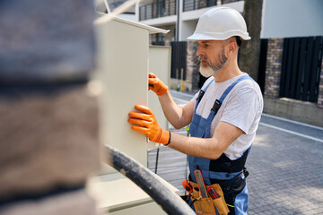 Skilled construction worker repairing external electrical distribution box