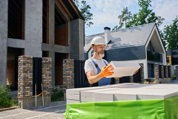 Construction worker is examining concrete paver block for masonry work