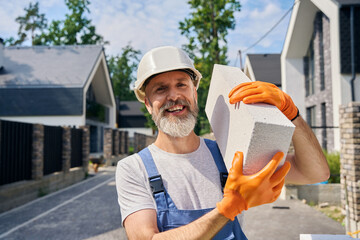 Cheerful bricklayer posing for camera on construction site in morning