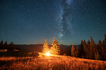 Night camping in mountains under starry sky. Tourist tents in campsite under sky full of stars with...
