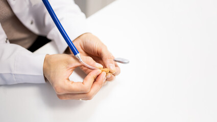 Photo of the hands of an otorhinolaryngologist using a stethoscope to listen to the sounds emitted by a behind-the-ear hearing aid. Hearing aid care concept.Checking the operation of your hearing aid.