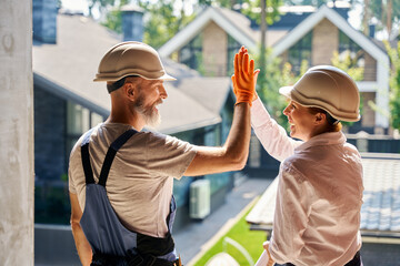 Team of cheerful construction professionals greeting one another on site