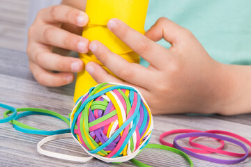 Preschooler hands putting rubber bands or erasers on cardboard roll. Development of kids motor skills, coordination logical thinking