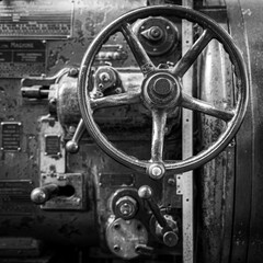 Obraz premium Flywheel of old industrial machine to raise or lower the pressure of a steam engine in black and white BW