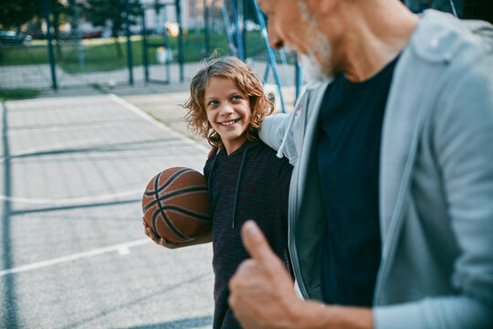 Grandfather and grandson playing basketball outside on a basketball court in the city