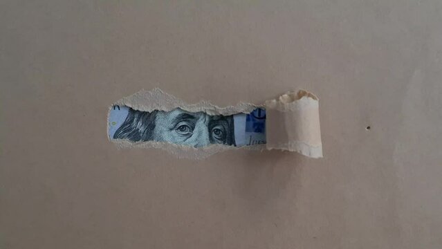 Paper torn and revealing dollar bill. Financial investment and cash income