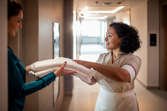 Happy hotel maid giving fresh towels to guest