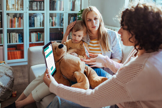 Young Lesbian Couple Using Tablet Health App For Daughter At Home