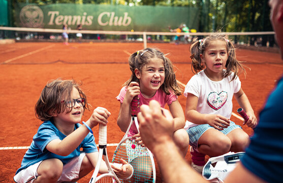 Tennis coach giving tips to little children during practice