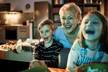 Happy children watching home movie with grandmother